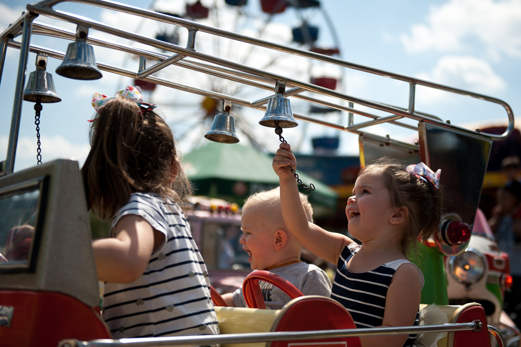 A Kaiserslautern Military Community child rings a bell while riding a carnival attraction during Freedom Fest at the Enlisted Club parking lot on Ramstein Air Base, Germany, July 4, 2017. Carnival rides, games, and cotton candy stands were set up for Freedom Fest, Ramstein’s way of celebrating Independence Day. (U.S. Air Force photo by Senior Airman Devin Boyer)