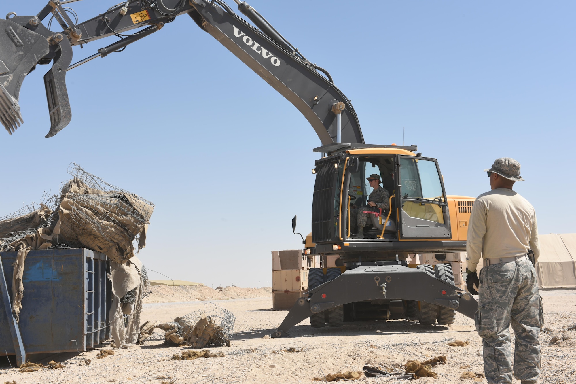 Staff Sgt. Victor Baez, a pavements and equipment operator with the 386th Expeditionary Civil Engineering Squadron, watches over U.S. Air Force Academy Cadet Austin Jacobs as he operates an excavator with a bucket attachment at an undisclosed location in Southwest Asia, June 27, 2017. The U.S. Air Force Academy cadets are deployed to the 386th Air Expeditionary Wing as part of the academy’s Operation Air Force program, which exposes cadets to a variety of career fields to aid them in their future career selections. (U.S. Air Force photo by Tech. Sgt. Jonathan Hehnly)