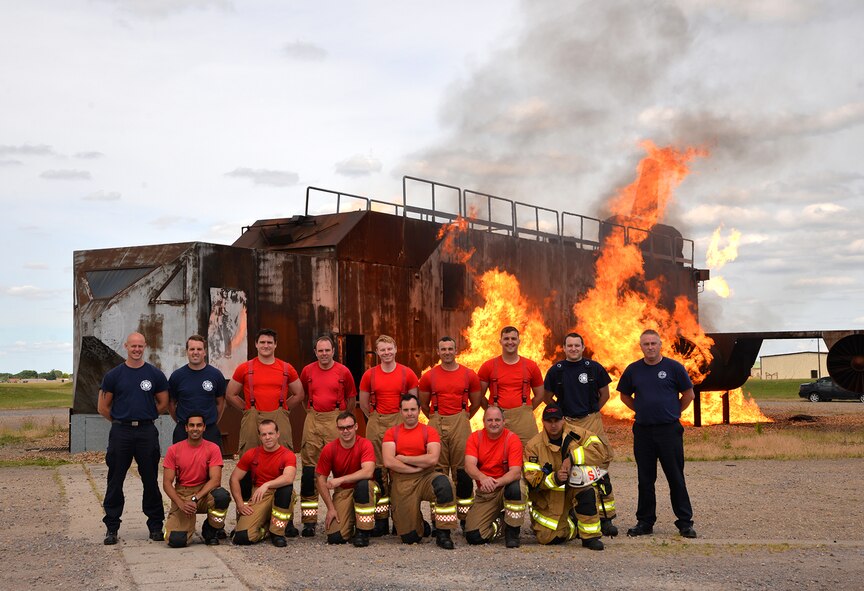 Firefighters from the 100th Civil Engineer Squadron Fire Department and Norfolk Fire and Rescue Service stand together by the live fire trainer June 26, 2017, on RAF Mildenhall, England. The British firefighters, most of whom are recruits at the end of their training course, visited RAF Mildenhall to gain familiarization training on KC-135 Stratotankers which increased effective communication and networking between on- and off-base fire departments. (U.S. Air Force photo by Karen Abeyasekere)