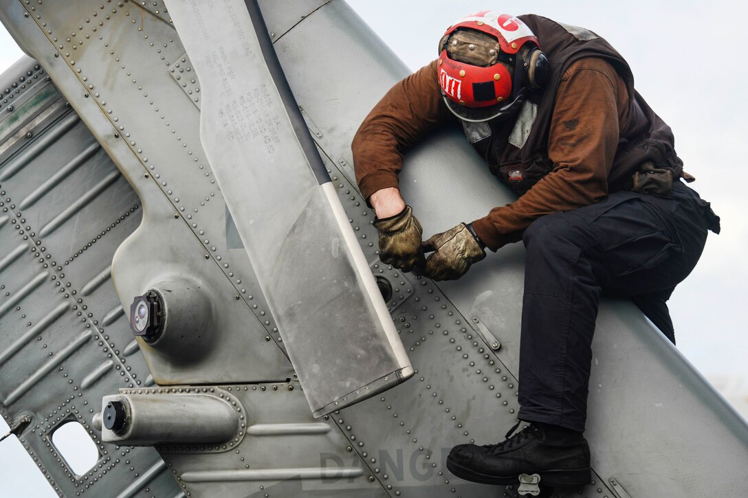 Navy Petty Officer 3rd Class Brandon Reynolds conducts post-flight maintenance on the tail of an MH-60R Seahawk helicopter aboard the aircraft carrier USS Nimitz in the Pacific Ocean, June 28, 2017. Reynolds is an aviation structural mechanic, and the helicopter is assigned to Helicopter Sea Combat Squadron 8. The Nimitz is on an underway period in the U.S. 7th Fleet area of operations. Navy photo by Navy Petty Officer 2nd Class Holly L. Herline