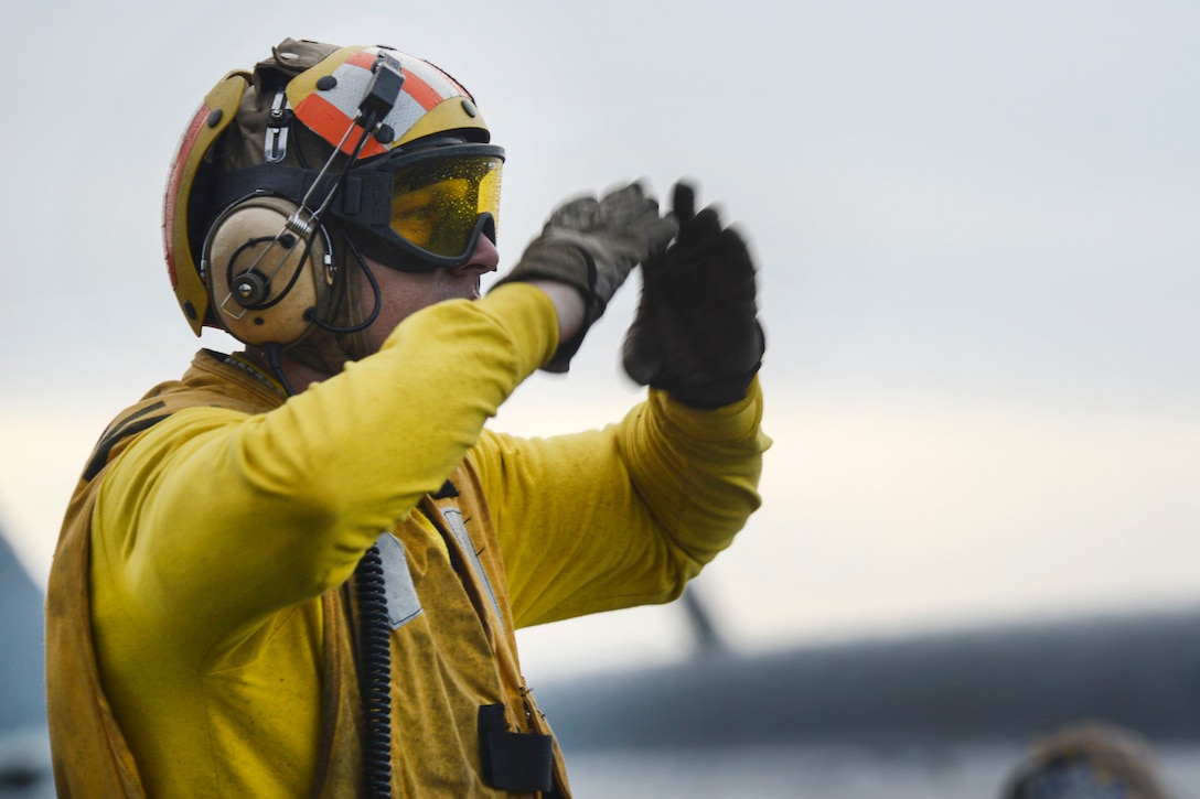 Navy Petty Officer 1st Class Kyle Krause signals to an aircraft on the flight deck of the aircraft carrier USS Nimitz in the Pacific Ocean, June 28, 2017. Krause is an aviation boatswain's mate. Navy photo by Petty Officer 2nd Class Holly L. Herline