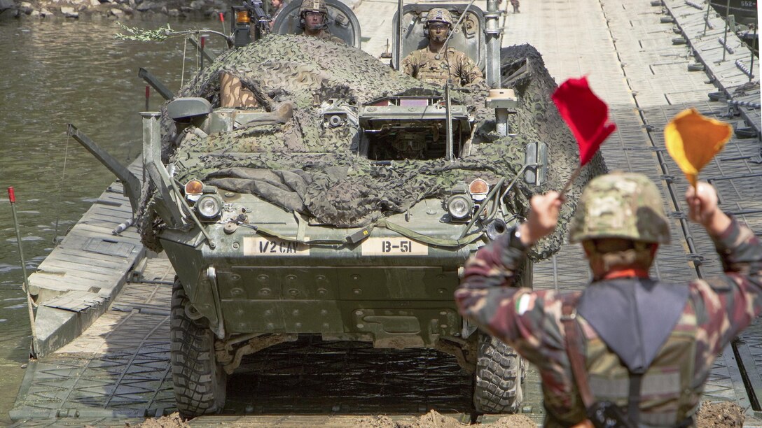 A Hungarian soldier directs U.S. soldiers driving a Stryker combat vehicle on a mobile bridge across the Mosoni-Duna River in Gyor, Hungary, July 4, 2017, during exercise Szentes Axe 17. The Hungarian exercise includes tactical bridging and water crossing operations in the area. Army photo by Staff Sgt. Jennifer Bunn