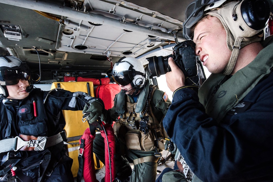 Navy Petty Officer 2nd Class Conor Minto, right, documents a plane guard patrol by an MH-60S Sea Hawk helicopter aboard the aircraft carrier USS Theodore Roosevelt in the Pacific Ocean, June 26, 2017. Navy photo by Petty Officer 3rd Class Anthony J. Rivera