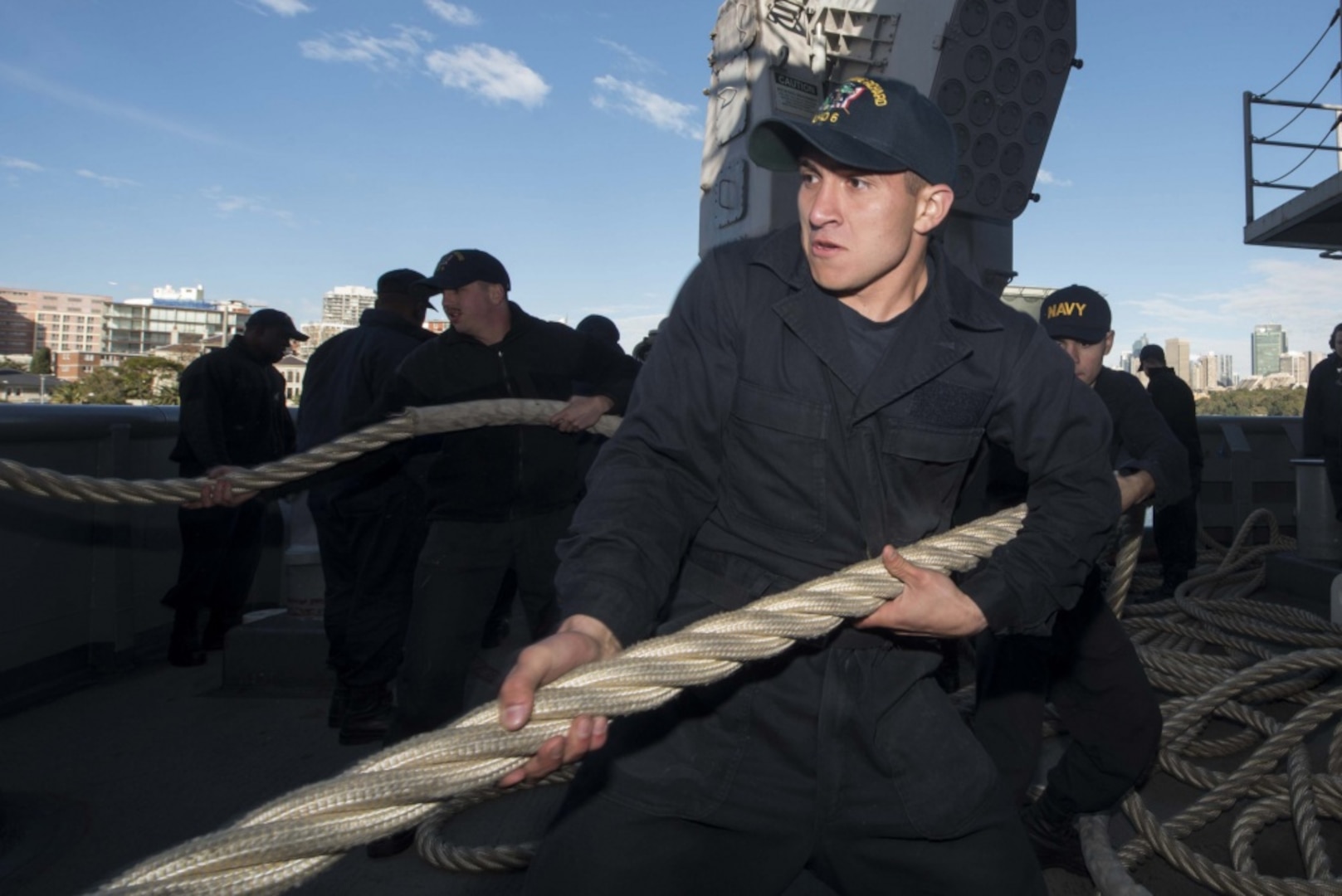 Seaman Apprentice Alex Ponce, from Morrilton, Ark., heaves a mooring line on the fantail of the amphibious assault ship USS Bonhomme Richard (LHD 6), July 3, 2017, as the ship departs Sydney following a four-day port visit and prepares to participate in Talisman Saber 2017. Talisman Saber is a biennial U.S.-Australian bilateral military exercise that combines a field training exercise and command post exercise to strengthen interoperability and response capabilities to uphold the tenets of the U.S.-Australian alliance. 