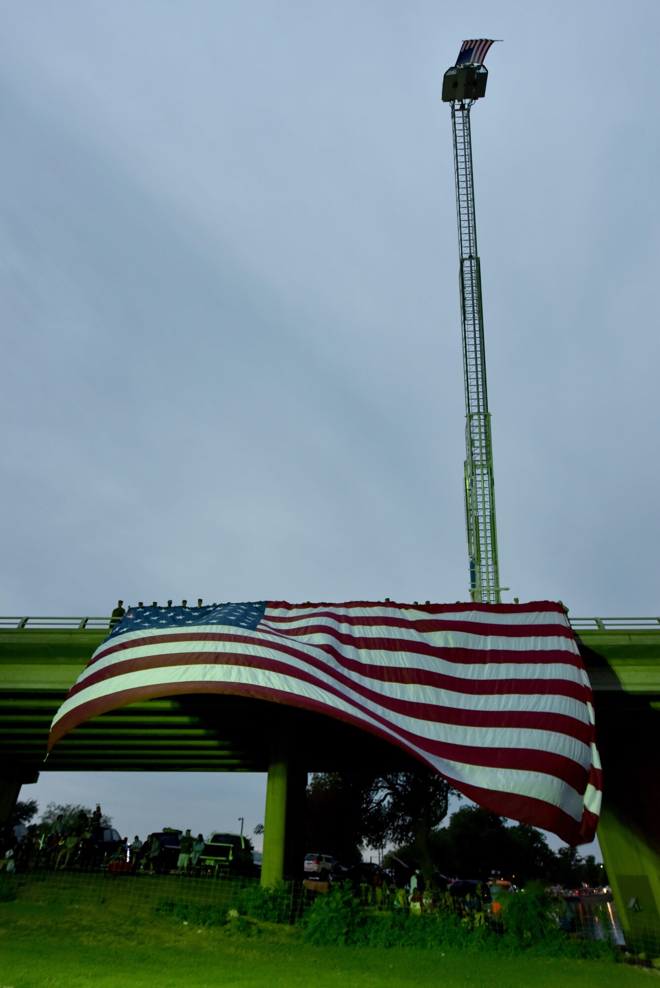 Goodfellow Air Force Base service members hold an American flag during the 30th Annual San Angelo Symphony July 3rd Pops Concert at the Bill Aylor Sr. Memorial RiverStage in San Angelo, Texas, July 3, 2017. The San Angelo Fire Department also hung their own flag for the event. (U.S. Air Force photo by Staff Sgt. Joshua Edwards/Released)