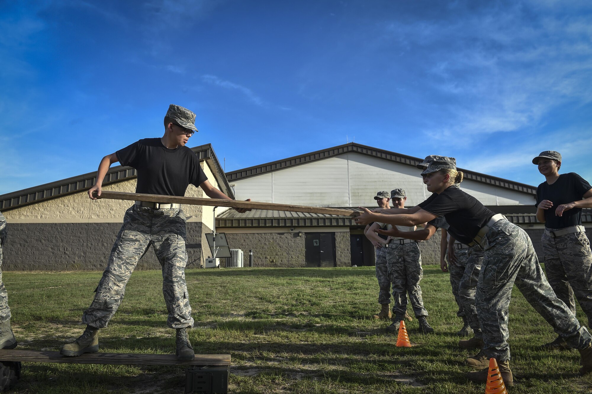 A Junior ROTC cadet hands a plank to a teammate to form a makeshift bridge during a leadership reaction exercise at Hurlburt Field, Fla., June 26, 2017. More than 50 JROTC cadets from five local high schools engaged in a variety of team-building and leadership exercises during Summer Leadership School to Hurlburt Field, June 26-30. (U.S. Air Force photo by Senior Airman Ryan Conroy)
