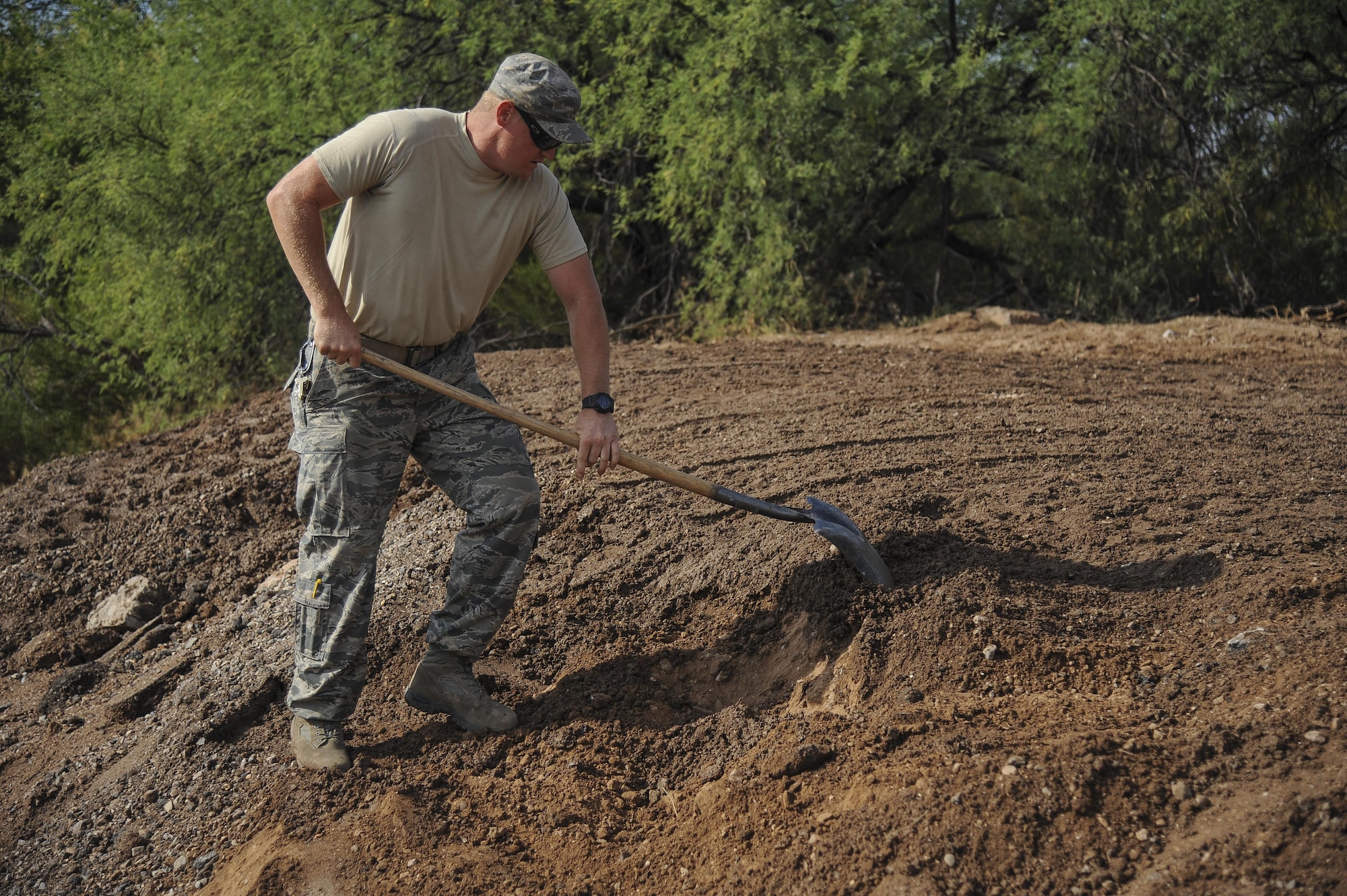 U.S. Air Force Staff Sgt. Chad McCay, 355th Civil Engineer Squadron pavements and equipment craftsman, shovels dirt at Davis-Monthan Air Force Base, Ariz., June 8, 2017. The 355th Civil Engineer Squadron pavements and equipment shop used approximately 2,500 tons of dirt to help reconstruct Atterbury Wash, a natural creek on the installation, in preparation for monsoon season.  (U.S. Air Force photo by Senior Airman Mya M. Crosby)