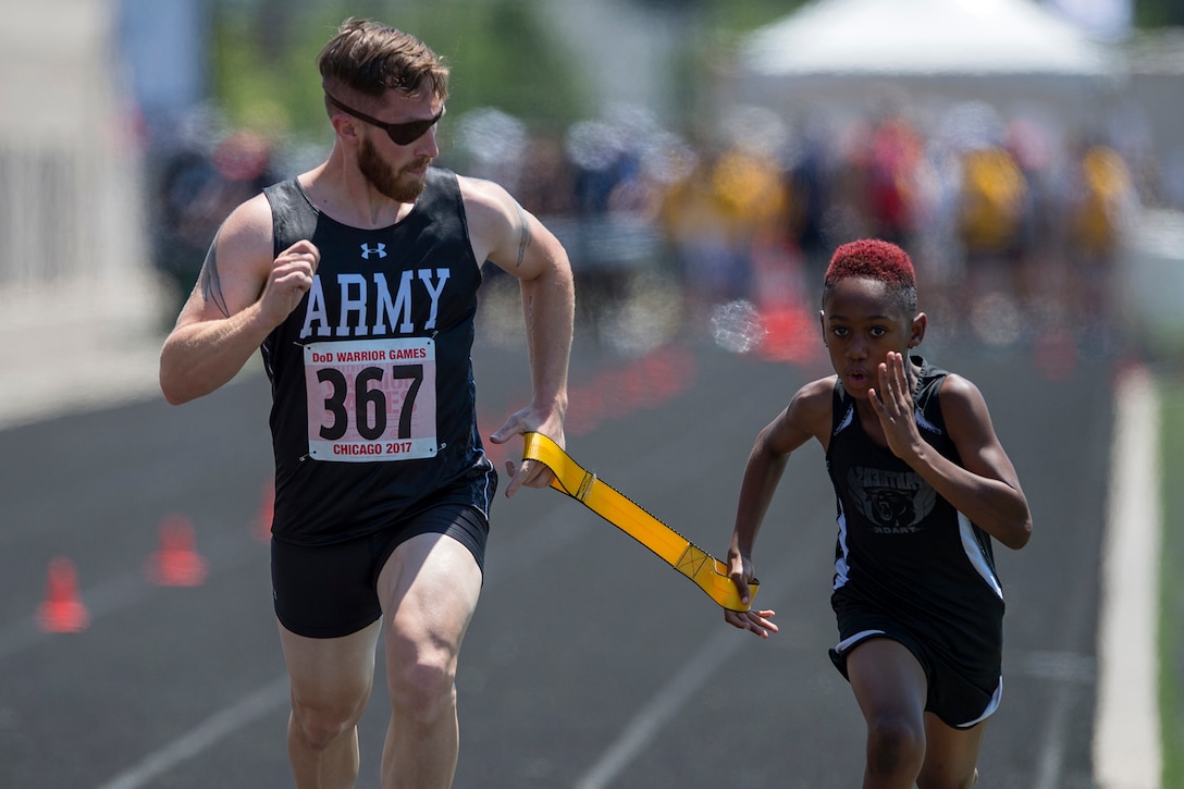 Visually impaired runner retired Army Spc. Michael Stephens races with 8-year-old Mika Blow before official races begin for the 2017 Department of Defense Warrior Games at Lane Tech High School in Chicago, July 2, 2017. DoD photo by EJ Hersom