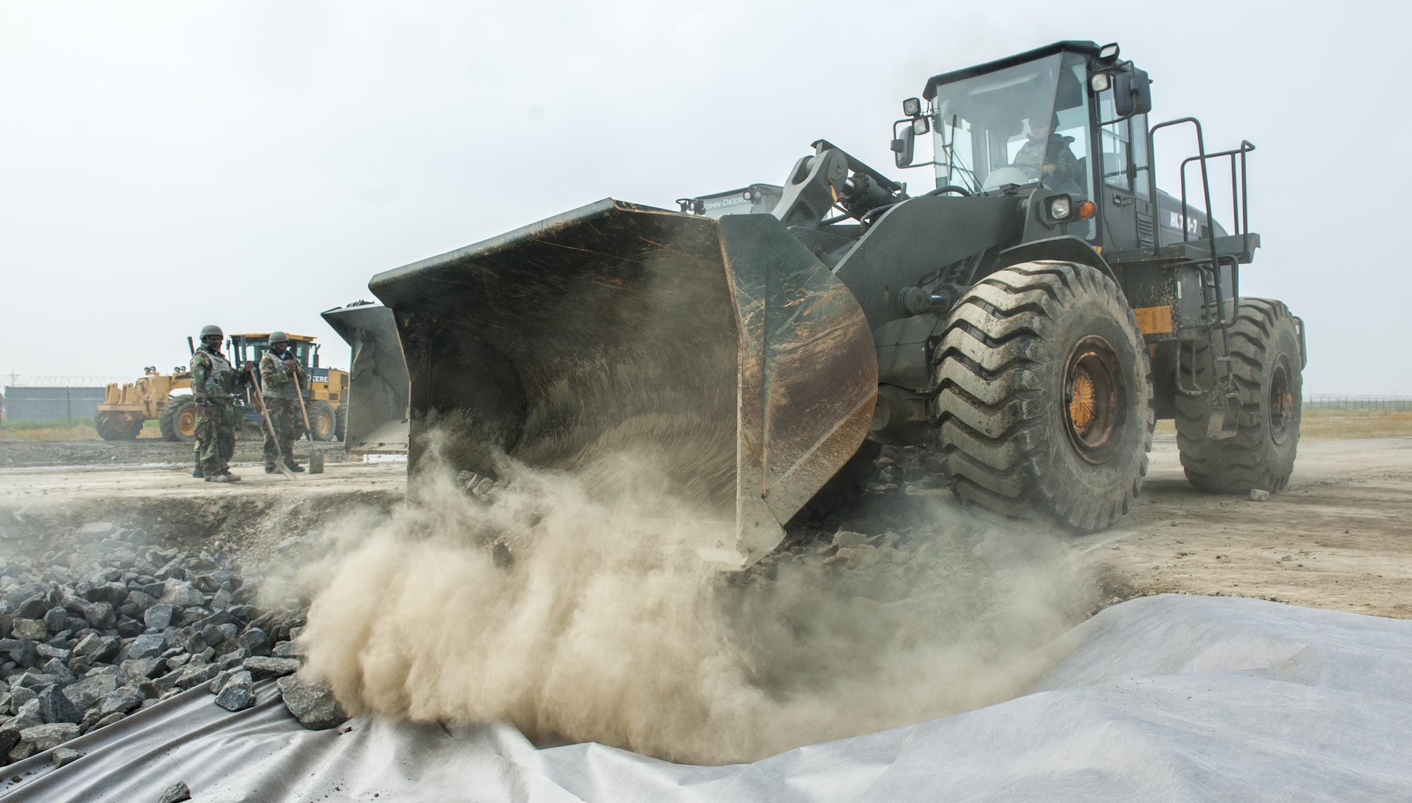 U.S. Air Force Airmen assigned to the 8th Civil Engineering Squadron pavement and construction section, stand by to assist a loader as it unloads rocks into a crater June 29, 2017, at Kunsan Air Base, Republic of Korea. The crater simulated runway battle damage, preventing aircraft takeoff. CES airmen were tasked to repair the damage as quickly as possible during an airfield damage repair exercise. (U.S. Air Force photo by Senior Airman Colville McFee/Released)