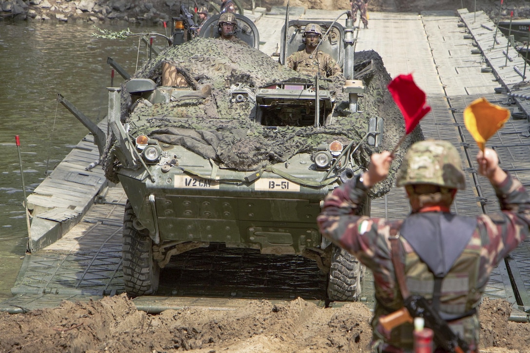 A Hungarian soldier directs U.S. soldiers driving a Stryker combat vehicle on a mobile bridge across the Mosoni-Duna River in Gyor, Hungary, July 4, 2017, during exercise Szentes Axe 17. The Hungarian exercise includes tactical bridging and water crossing operations in the area. Army photo by Staff Sgt. Jennifer Bunn