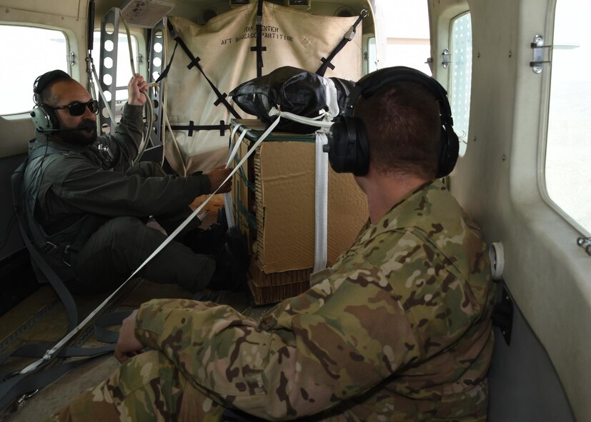 An Afghan Air Force C-208 pilot, prepares to deliver supplies, over Southeast, Afghanistan, as Tech. Sgt. Brian Wahl, Train, Advise, Assist Command-Air, 538th Air Expeditionary Advisory Squadron C-208 loadmaster advisor, stands by for assistance during an aerial resupply mission on June 28, 2017. This was the first operational airdrop performed by AAF aircrew. The AAF successfully delivered 800 pounds of supplies to Afghan Border Police at their coordinated drop zone. (U.S. Air Force photo by Tech. Sgt. Veronica Pierce)
