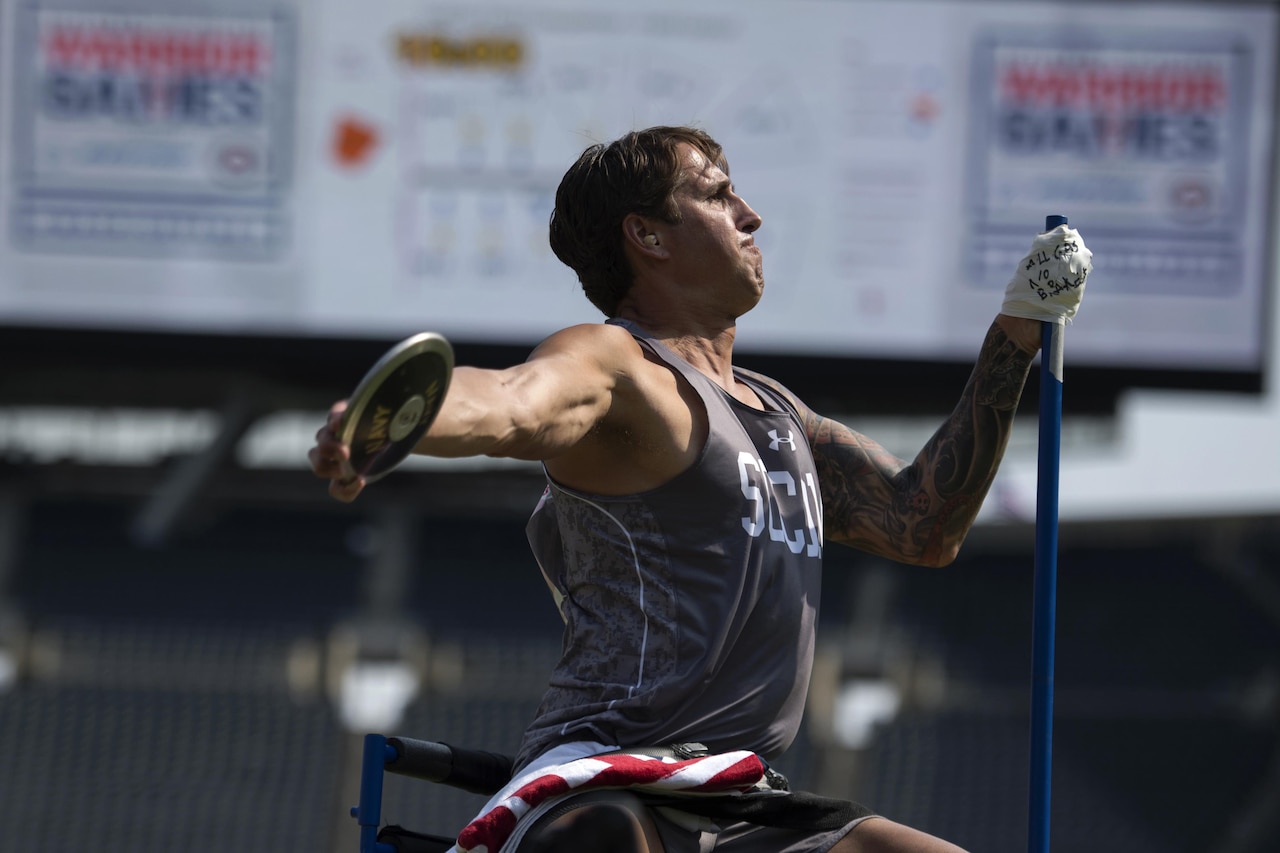 Navy Lt. Cmdr Ramesh Haytasingh throws seated discus in the 2017 Department of Defense Warrior Games in Chicago, July 5, 2017. An inscription on the tape holding his hand to support pole reads ‘All Gas No Brakes.’ DoD photo by EJ Hersom