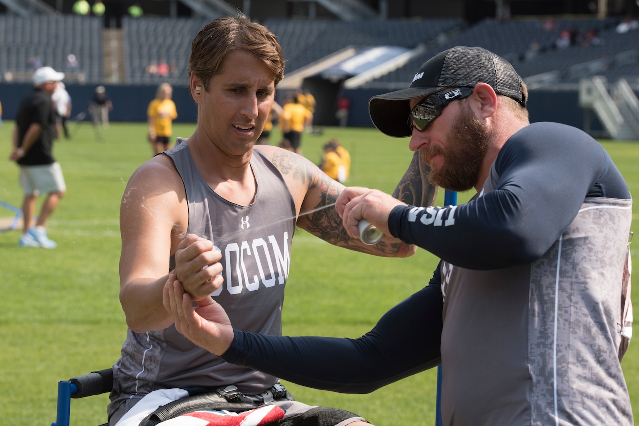 SOCOM's veteran Sgt. First Class Joshua Lindstrom sprays team mate Navy Lt. Cmdr. Ramesh Haytasingh's hand with sticky spray before Haytasingh throws a discus during the 2017 Department of Defense (DoD) Warrior Games at Soldier Field in Chicago, Ill., July 5, 2017. The DoD Warrior Games are an annual event allowing wounded, ill and injured service members and veterans to compete in Paralympic-style sports including archery, cycling, field, shooting, sitting volleyball, swimming, track and wheelchair basketball.    (DoD photo by Roger L. Wollenberg)