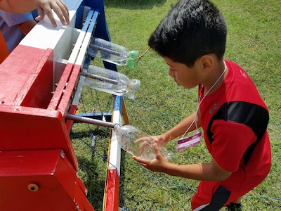 KING GEORGE. Va. (June 29, 2017) - A middle school student prepares his water rocket for launch at the 2017 Naval Surface Warfare Center Dahlgren Division sponsored STEM Summer Academy, held June 26-30. Camp activities also included ten robotic challenges; exploring epidemiology; building and destructively testing a tower from balsa wood with the goal of maximizing the strength to weight ratio; predicting the number of each color of M&Ms in a large bag after compiling statistics on numbers in smaller bags; and building a boat out of foil and straws with the aim of maximizing its cargo carrying capacity.