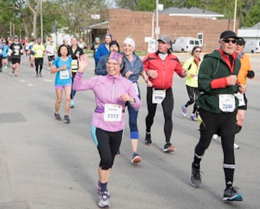 Irene Macallister of the Construction Engineering Research Laboratory waves at the ‘Discount Rhythm Dukes’ band in front of Second Hand Rose on Main Street in Urbana during the Ninth Illinois Marathon.
