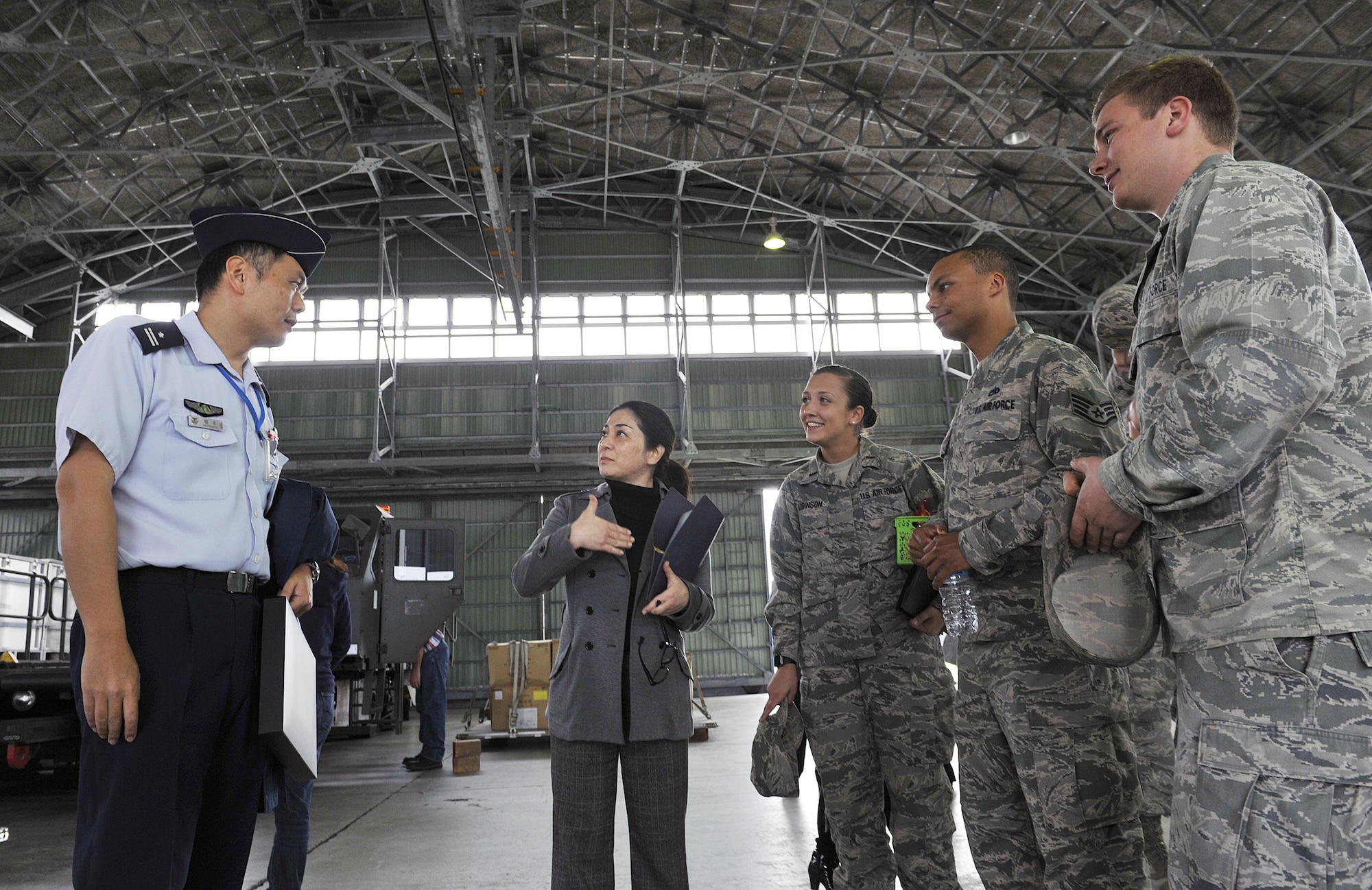 Japan Air Self Defense Force Maj. Toshiro Hatamoto, headquarters, Southwestern Composite Air Division logistic planning transportation section chief, speaks with U.S. Air Force 733rd Air Mobility Squadron members about the JASDF side of Aerial Port operations, March 10, 2016, at Naha Air Base, Japan. The 733rd AMS toured Naha Air Base to build relations between the U.S. Air Force and JASDF partners. (U.S. Air Force photo by Naoto Anazawa)