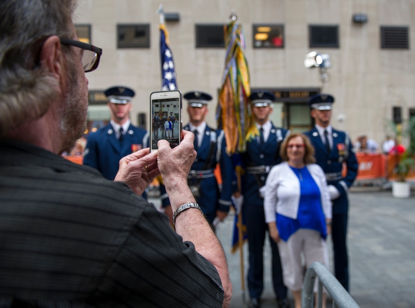 An audience member takes a photo of his wife posing with members of the U.S. Air Force Honor Guard following a taping of the Today Show in New York City, July 4, 2017. The U.S. Air Force Band ceremonial brass ensemble and Honor Guard color team were there to represent the men and women of the U.S. Air Force and spread patriotism during Independence Day celebrations on the Today Show and a New York Yankees baseball game. (US Air Force Photo by Airman 1st Class Gabrielle Spalding)