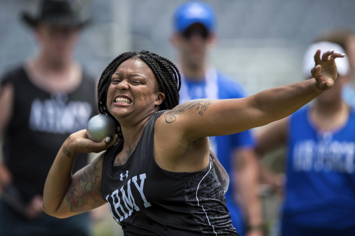 A female soldier grits her teeth as she throws a shot put.