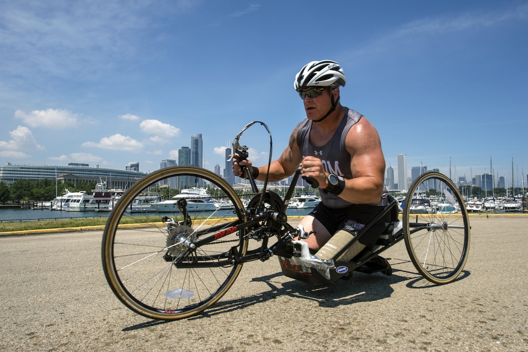 A soldier steers a handcycle with a Chicago skyline backdrop.