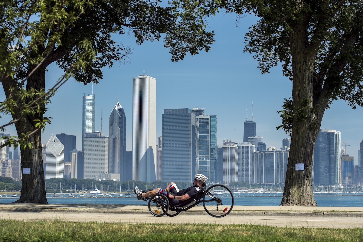 An airman races a recumbent cycle with the Chicago skyline in the background.