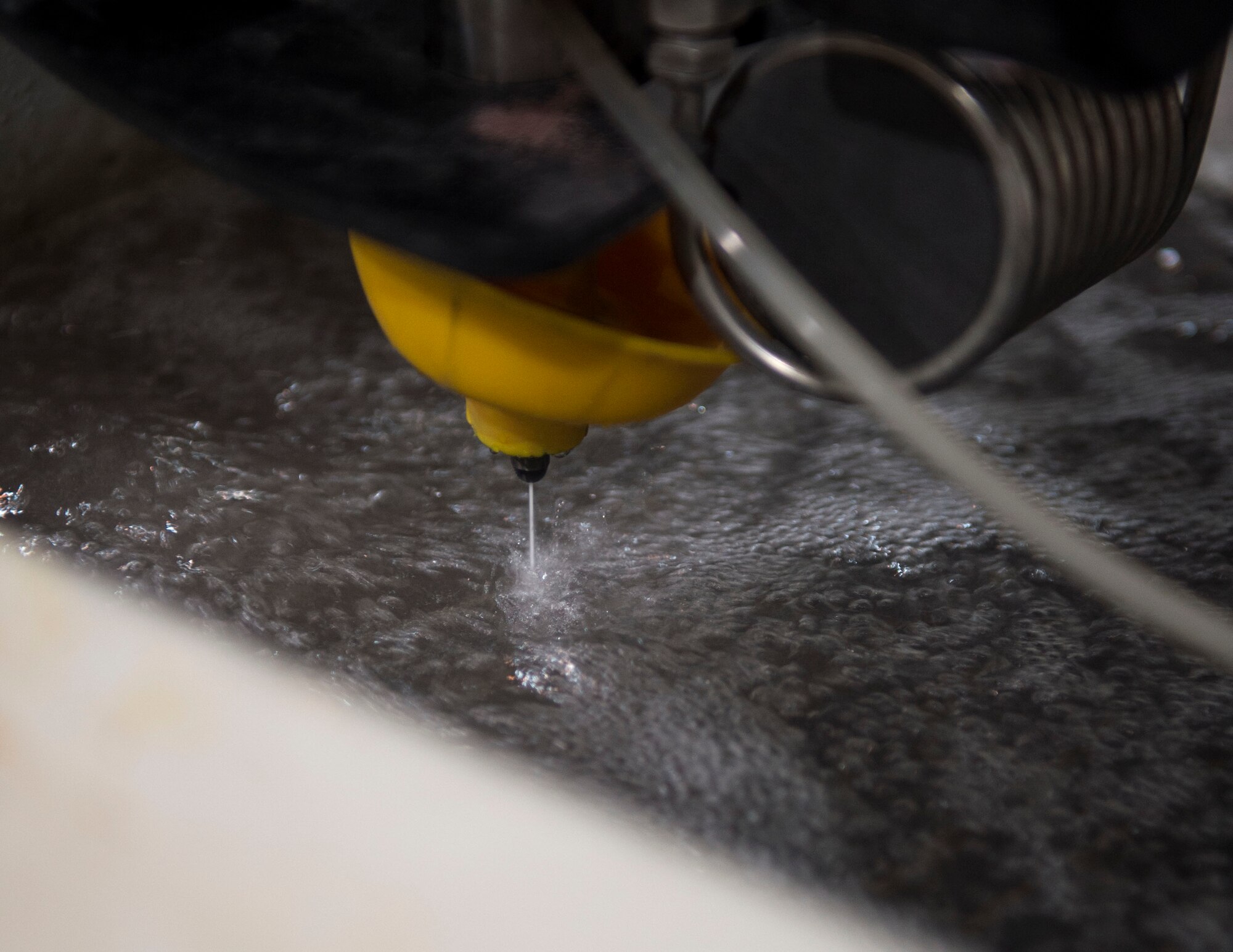 The abrasive waterjet cutting machine located in the fabrication shop of the 379th Expeditionary Maintenance Squadron uses a high velocity coherent stream of 98% water and 2% sand to cut through almost any material at Al Udeid Air Base, Qatar, June 5, 2017. The abrasive waterjet cutting machine allows the airmen to create a wide range of aircraft parts or tools needed to complete the mission in an expedited and a cost effective manner. (U.S. Air Force photo by Tech. Sgt. Amy M. Lovgren)