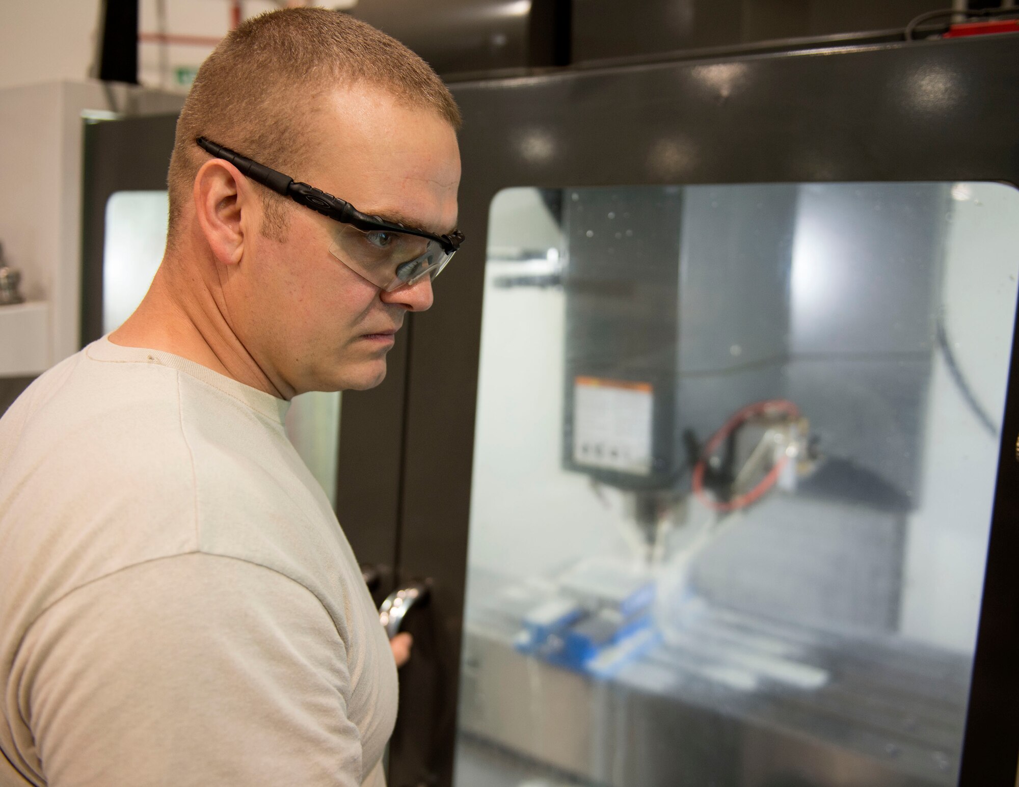 U.S. Air Force Staff Andrew Walker, a fabrication specialist with the 379th Expeditionary Maintenance Squadron uses a computer numerical control machine at Al Udeid Air Base, Qatar, June 5, 2017. The CNC allows Walker and other machinists to increase the speed of the manufacturing and reduce the wait time for new aircraft parts. (U.S. Air Force photo by Tech. Sgt. Amy M. Lovgren)