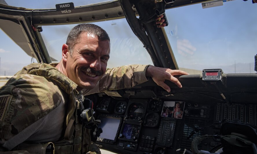 Maj. Paul Brighton, an 83rd Expeditionary Rescue Squadron HH-60G Pave Hawk pilot, poses for with a photo of his family on Bagram Airfield, Afghanistan, July 4, 2017. Brighton, who is deployed out of Davis-Monthan Air Force Base, Arizona, flies the helicopter into hostile territory, ensuring pararescuemen reach their destination and provide life-saving medical care to wounded ground troops. (U.S. Air Force photo by Staff Sgt. Benjamin Gonsier) 