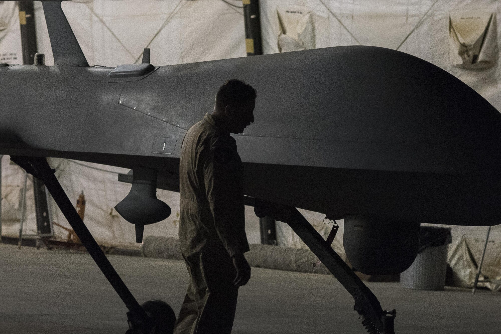 Lt. Col. Douglas, 361st Expeditionary Attack Squadron commander, inspects an MQ-1B Predator after its last combat flight assigned to the 361st EATKS, July 2, 2017, in Southwest Asia. In the 18 months the MQ-1B was assigned to the 361st Expeditionary Reconnaissance Squadron, later designated as the 361st EATKS, its aircrew flew the aircraft on more than 2,000 combat missions, 36,000 persistence attack and reconnaissance hours, and fired 358 AGM-114 Hellfire missiles, greatly contributing to the fight against ISIS. (U.S. Air Force photo/Senior Airman Damon Kasberg)