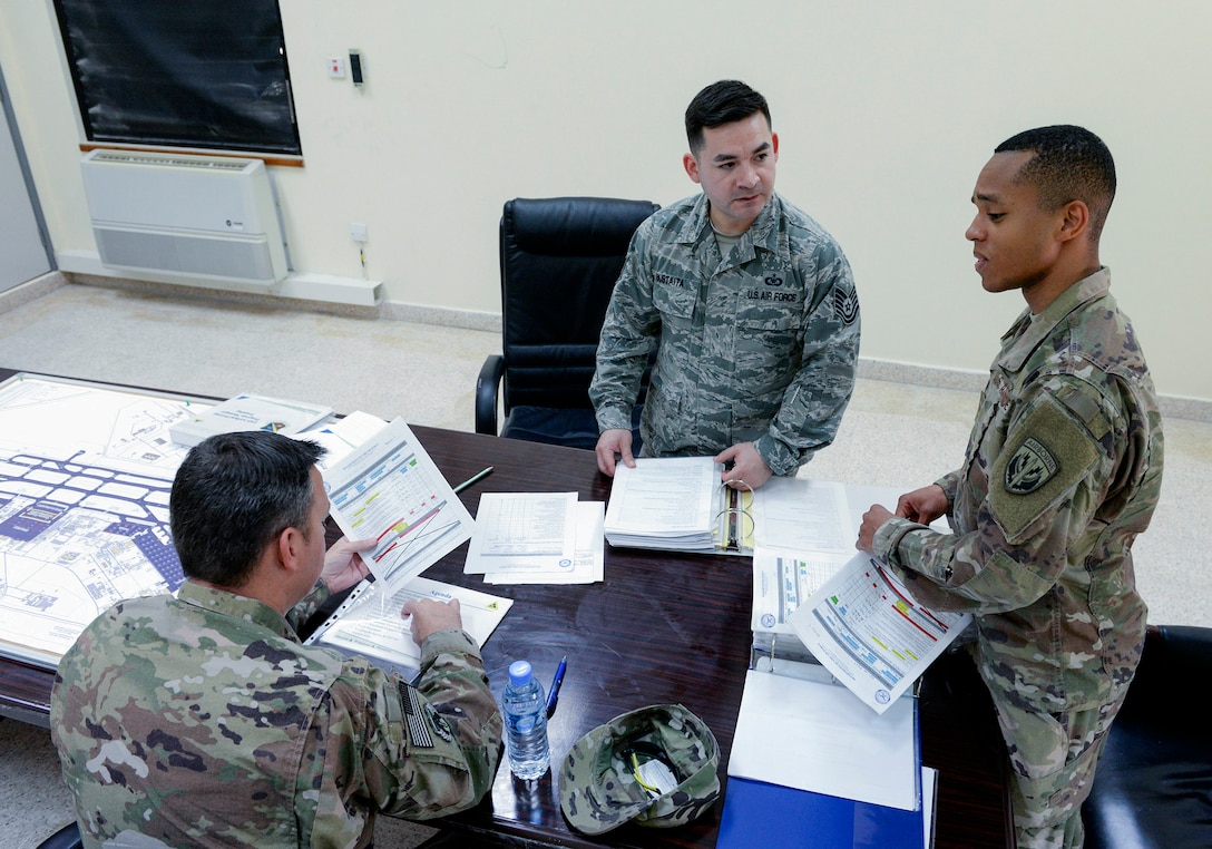 U.S. Air Force Tech. Sgt. Santino Sustaita, airfield driving program manager assigned to the 379th Expeditionary Office of Strategic Services, center, reviews training material with airfield driving trainers at Al Udeid, Air Force Base, Qatar, June 7, 2017. Airfield Management oversees more than 20 million square feet of airfield at Al Udeid in addition to overseeing the airfield driving program and filing all flight plans for flights arriving to and departing from the base. (U.S. Air National Guard photo by Tech. Sgt. Bradly A. Schneider/Released)