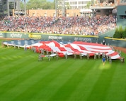 A group of about 80 military men and women in uniform unfurl an enormous American Flag, carry it onto the field, and wave it during the opening ceremony at the Atlanta Braves game July 4, 2017 at SunTrust Park in Atlanta, Georgia. The group was comprised of local members from the Army, Georgia National Guard, Air National Guard and Air Force Reserve. (U.S. Air Force photo by Staff Sgt. Jaimi L. Upthegrove)