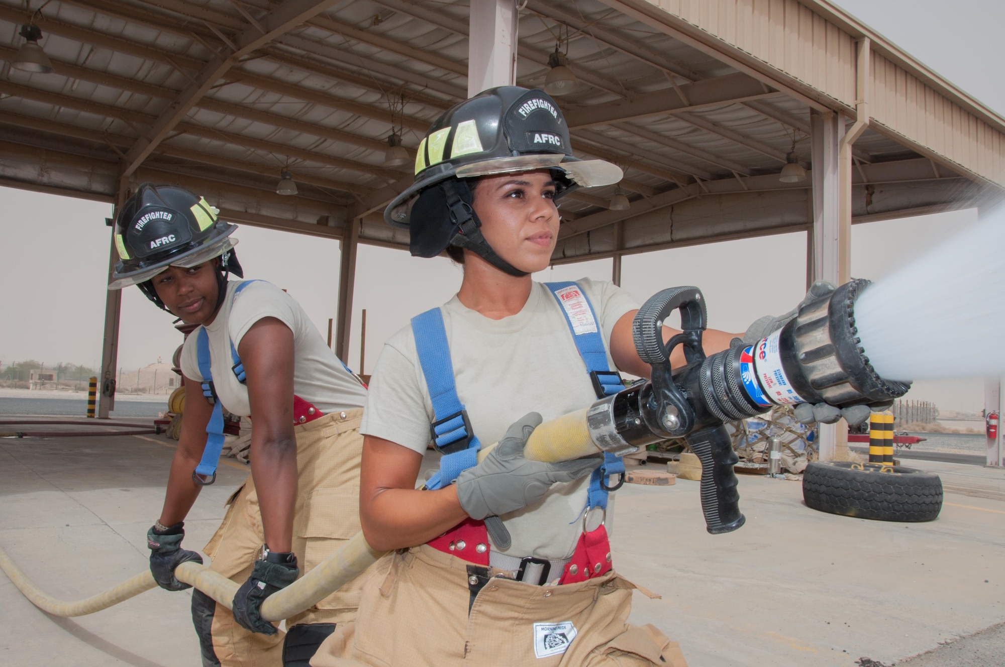 Staff Sgt. Jessica Mendoza (right) operates a hand line with assistance from Senior Airman Christa Dennis at one of the 386th Air Expeditionary Wing's fire stations an undisclosed location in Southwest Asia, June 25, 2017. Mendoza and Dennis are firefighters assigned to the 386th Civil Engineer Squadron.(U.S. Air Force photo by Master Sgt. Eric M. Sharman)