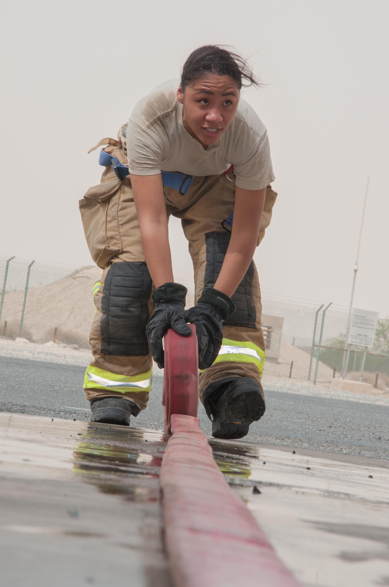 Senior Airman Ayanna Gaskin, a firefighter assigned to the 386th Civil Engineer Squadron, rolls a fire hose prior to storage  in the fire truck parking area at an undisclosed location in Southwest Asia, June 25, 2017. (U.S. Air Force photo by Master Sgt. Eric M. Sharman)