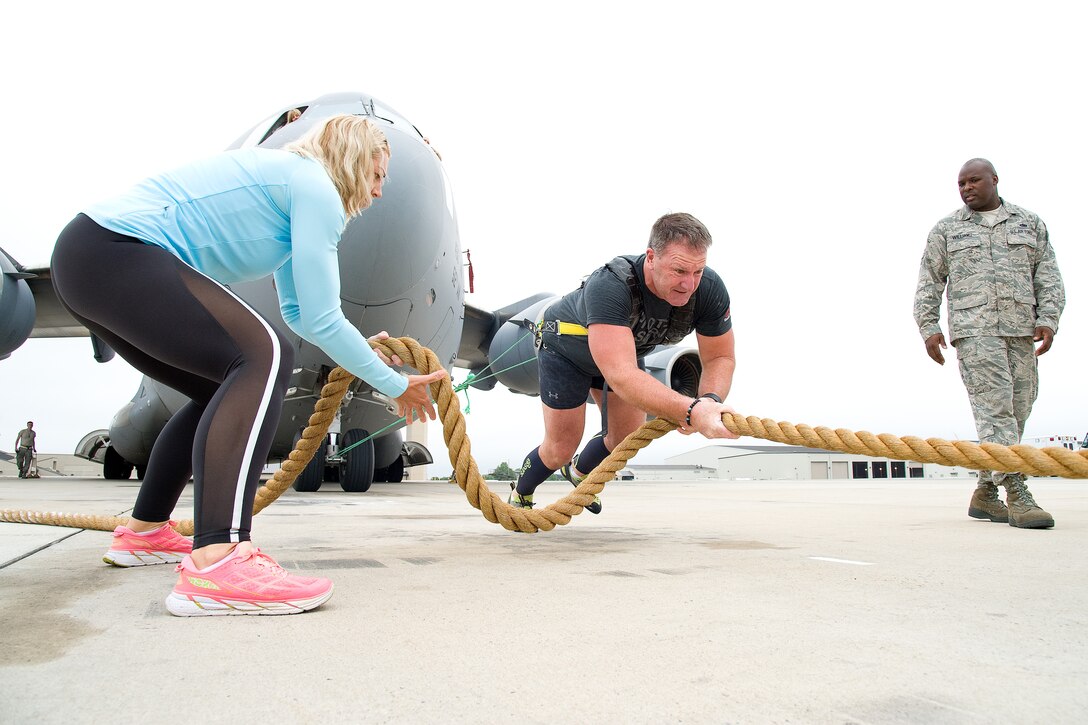 Cmdr. Grant Edwards, Australian Federal Police, Embassy of Australia, Washington, D.C., nears the end of his first attempt at pulling a C-17 Globemaster III, June 16, 2017, on Dover Air Force Base, Del. Kate Lord, Edwards’ wife, left, takes up the excess rope used for grip by Edwards as Staff Sgt. Aaron Williams, 736th Aircraft Maintenance Squadron crew chief, monitors his safety and signals to aircraft maintainers for brakes and chocks at the end of his first attempt. The rope was attached to a tow vehicle. (U.S. Air Force photo by Roland Balik)