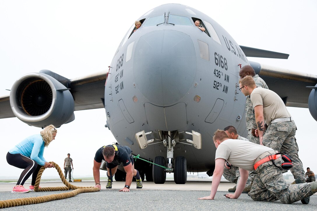 From the flight deck, Master Sgt. Christine King, top left, and Tech. Sgt. Brinnae Wigley, top right, both 712th Aircraft Maintenance Squadron crew chiefs, watch Cmdr. Grant Edwards, Australian Federal Police, Embassy of Australia, Washington, D.C., repositions himself on his third attempt at pulling a C-17 Globemaster III weighing approximately 418,898 pounds, June 16, 2017, on Dover Air Force Base, Del. Kate Lord, Edwards’ wife, left, and members of the 736th Aircraft Maintenance Squadron cheer on Edwards, an Australian strongman athlete, during this attempt. Edwards is scheduled to attempt pulling a C-17 during the “Thunder Over Dover: 2017 Dover AFB Open House,” Aug. 26-27. (U.S. Air Force photo by Roland Balik)