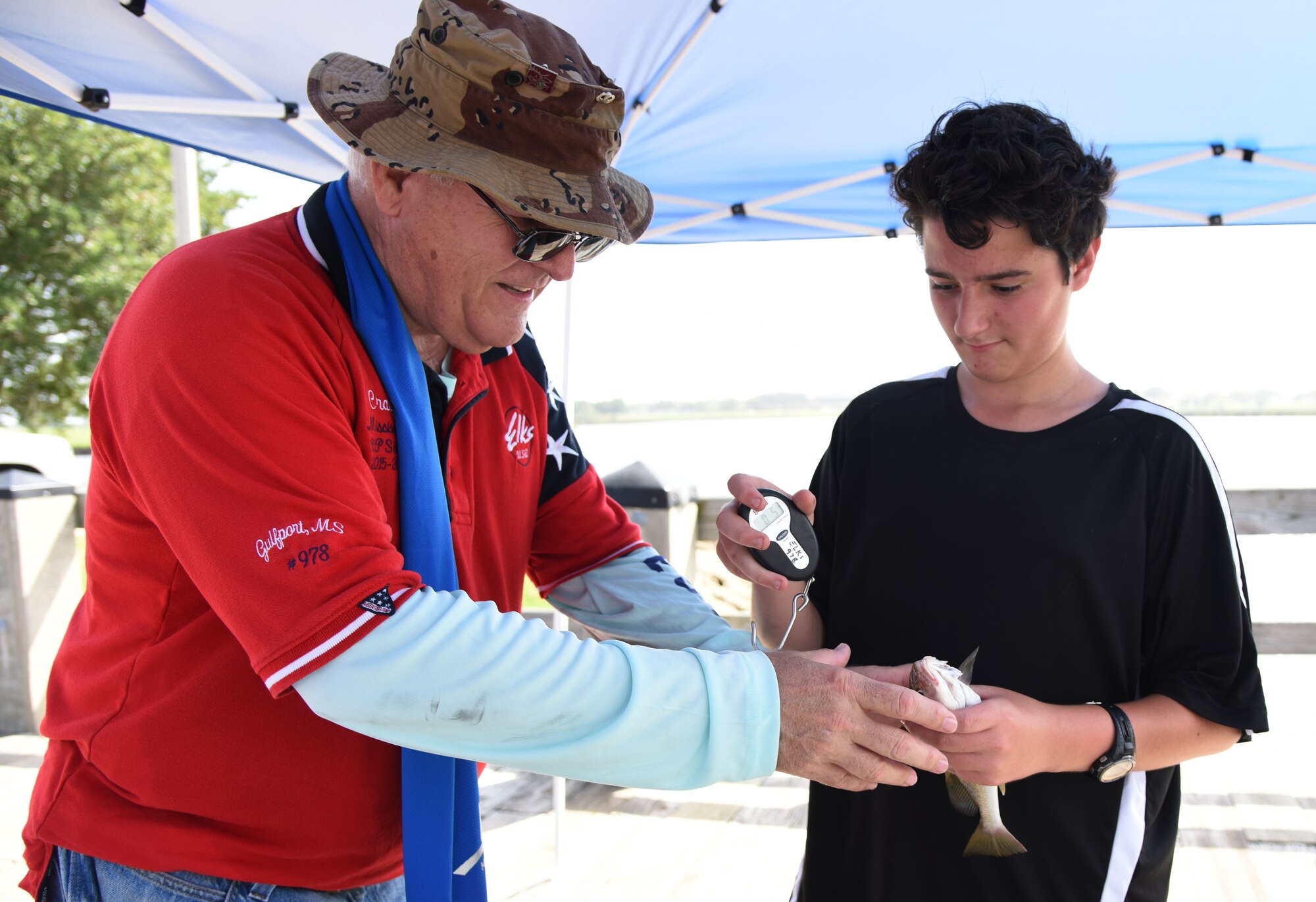 Craig Huch, Gulfport Elks Lodge volunteer, measures a fish caught by Patrick Peoples, son of retired Navy Beldan Peoples, at the kids’ fishing rodeo during the Pops in the Park event at Marina Park July 1, 2017, on Keesler Air Force Base, Miss. The event also included a mullet toss, fireworks display and music performances. (U.S. Air Force photo by Kemberly Groue)