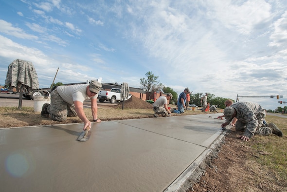 Members of the 5th Civil Engineer Squadron flatten concrete for a sidewalk at Minot Air Force Base, N.D., June 29, 2017. CE Airmen use various equipment when remodeling the sidewalk, from fresno trowels to curing compounds. (U.S. Air Force photo by Airman 1st Class Jonathan McElderry)