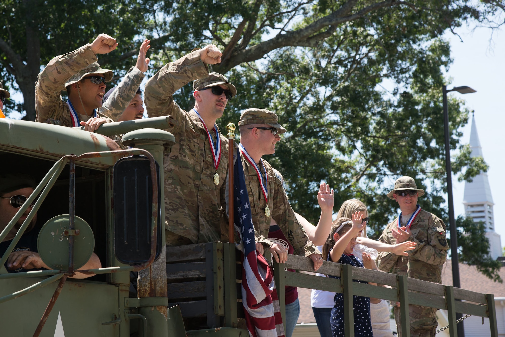 Airmen wave from a vintage military vehicle during the 2016 Heroes Homecoming parade at Hanscom AFB, Mass., July 21. The annual celebration honors military and civilian personnel who have returned from deployment in the past year. (U.S. Air Force Photo by Mark Herlihy)