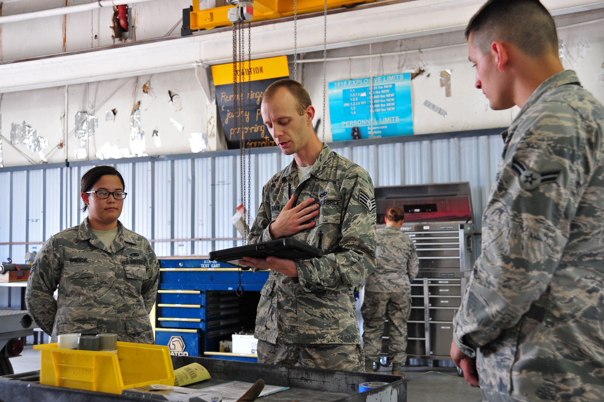 U.S. Air Force Staff Sgt. Joshua Bradley, 20th Equipment Maintenance Squadron (EMS) tactical aircraft maintainer, center, reads a technical order to Senior Airman Keri Brock, left, and Airman 1st Class Ty Lerum, 20th EMS precision guided munitions technicians, at Shaw Air Force Base, S.C., June 27, 2017. The technical order dictates every step the Airmen must take while inspecting munitions. (U.S. Air Force photo by Airman 1st Class Kathryn R.C. Reaves)