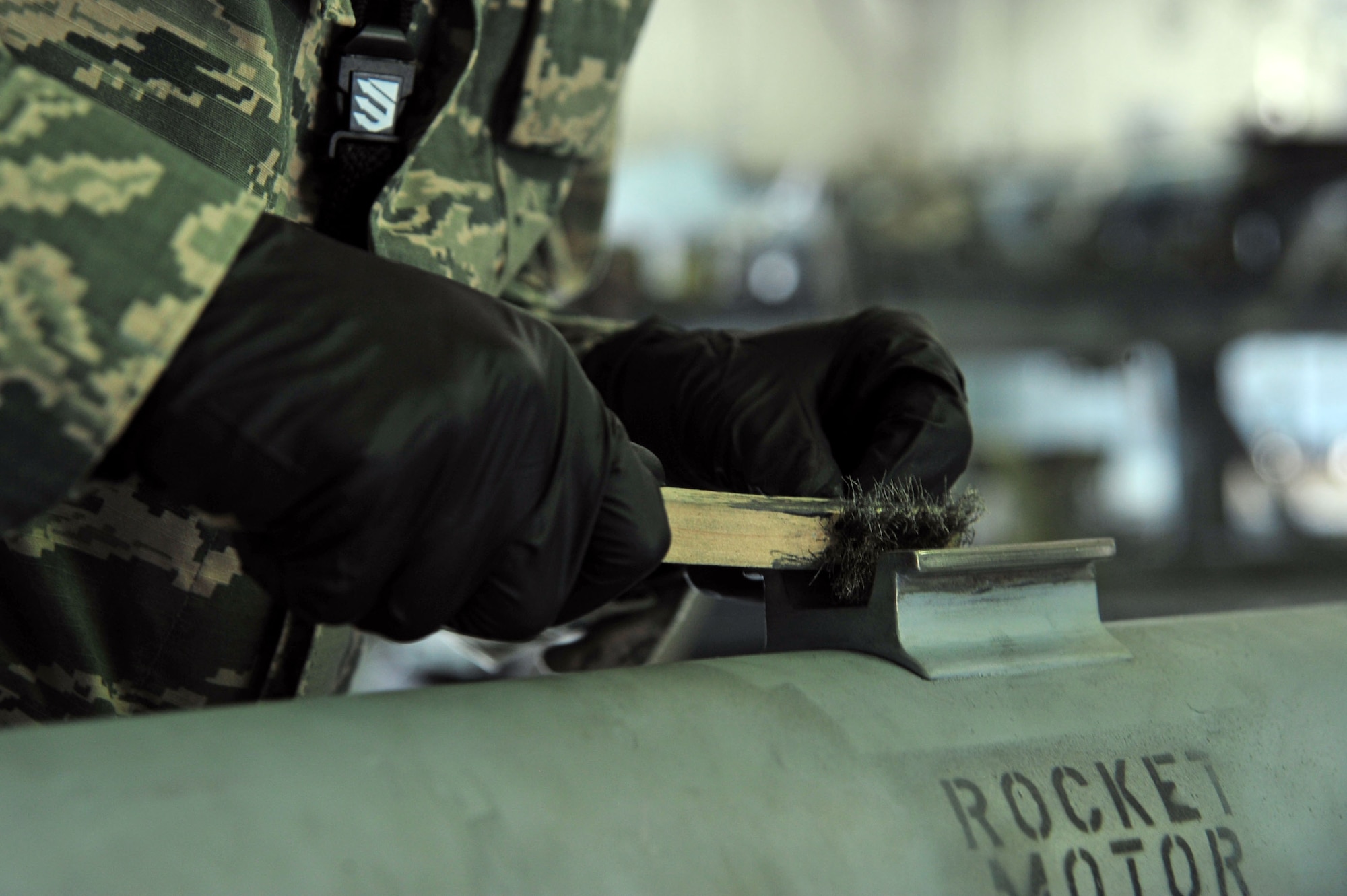 U.S. Air Force Airman 1st Class Ty Lerum, 20th Equipment Maintenance Squadron precision guided munitions technician, uses a wire brush to remove Solid Film on an AIM-9 Sidewinder missile hanger at Shaw Air Force Base, S.C., June 27, 2017. The lubricant film protects the hanger when the munition is attached to an aircraft. (U.S. Air Force photo by Airman 1st Class Kathryn R.C. Reaves)