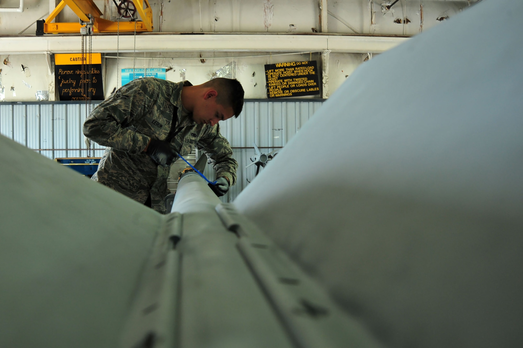 U.S. Air Force Airman 1st Class Ty Lerum, 20th Equipment Maintenance Squadron precision guided munitions technician, places tape on an AIM-9 Sidewinder missile at Shaw Air Force Base, S.C., June 27, 2017. The tape isolated areas of the munition that needed to be repainted due to wear or exposure of bare metal following the removal of rust. (U.S. Air Force photo by Airman 1st Class Kathryn R.C. Reaves)