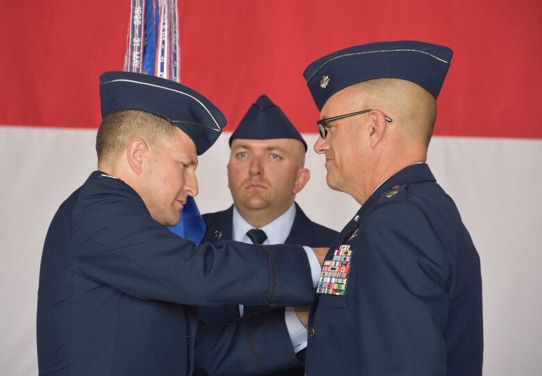 Col. Dominic Setka, 552nd Air Control Group commander, pins the command badge on Lt. Col. Kelly Shelton, 552nd Air Control Networks Squadron commander, during a change of command ceremony June 27. Holding the unit guidon is Master Sgt. Benjamin Jetland, 552nd ACNS first sergeant. (Air Force photo by Ron Mullan)
