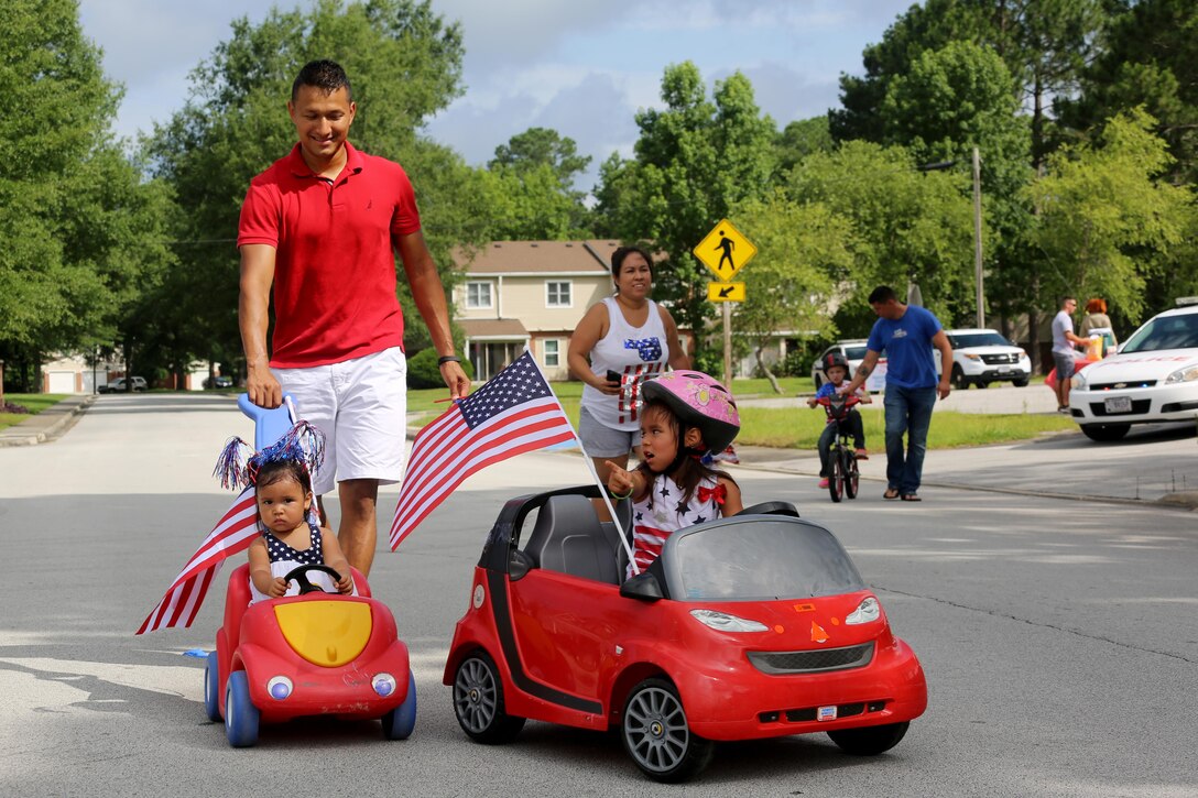 Staff Sgt. Elias Velasquez and his two daughters, Annabelle, 2, and Ashley, 8, trek through their neighborhood during the first Independence Day Youth Parade at Marine Corps Air Station Cherry Point, N.C., July 4, 2017. The patriotic event catered to younger family members, but encouraged the larger community to come together. Velasquez is the quality assurance representative assigned to Marine Aerial Refueler Transport Squadron 252, 2nd Marine Aircraft Wing. (U.S. Marine Corps photo by Cpl. Jason Jimenez/ Released)