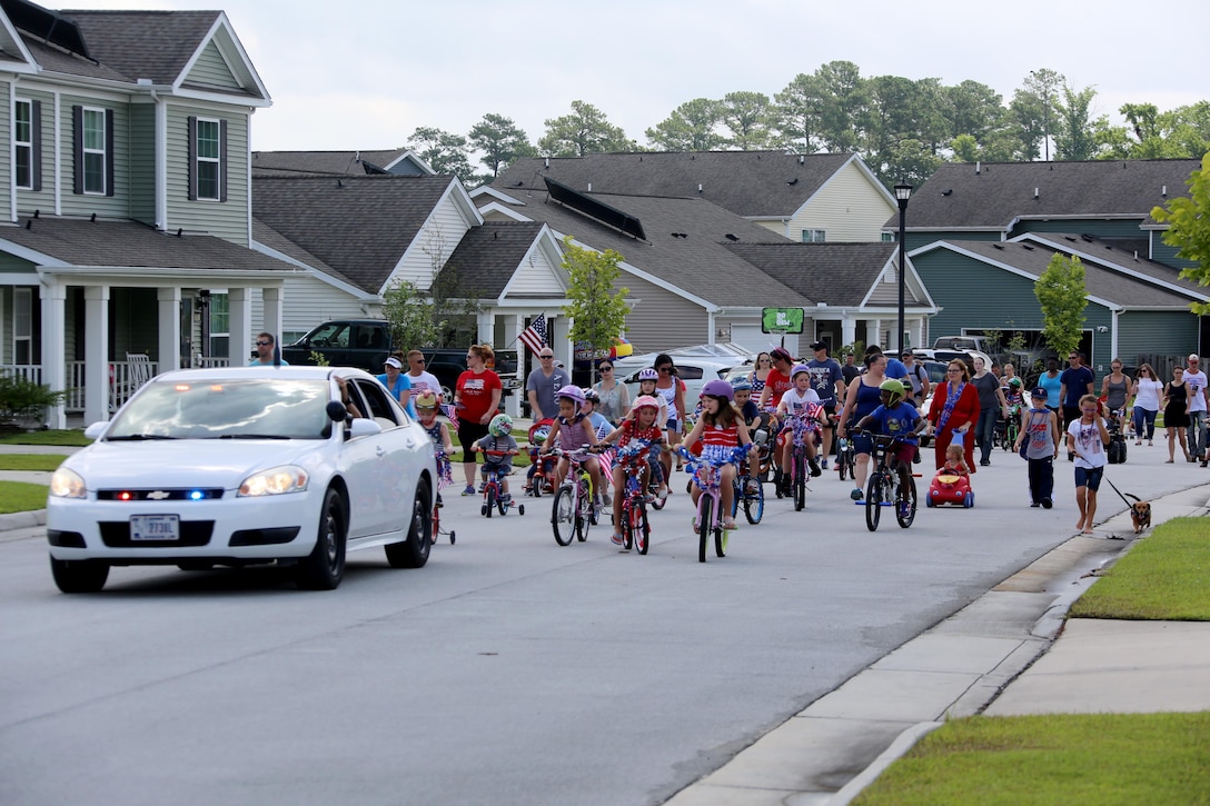 Community members parade through their neighborhood during the first Independence Day Youth Parade at Marine Corps Air Station Cherry Point, N.C., July 4, 2017. The Cherry Point Provost Marshal’s Office ensured the Independence Day fun was enjoyed safely with their vehicles leading participants through the mile-long path. Cherry Point’s own McGruff the Crime Dog and Sparky the Fire Dog also interacted with children. Nearly 100 members of the Cherry Point community gathered for the festivities. (U.S. Marine Corps photo by Cpl. Jason Jimenez/ Released)