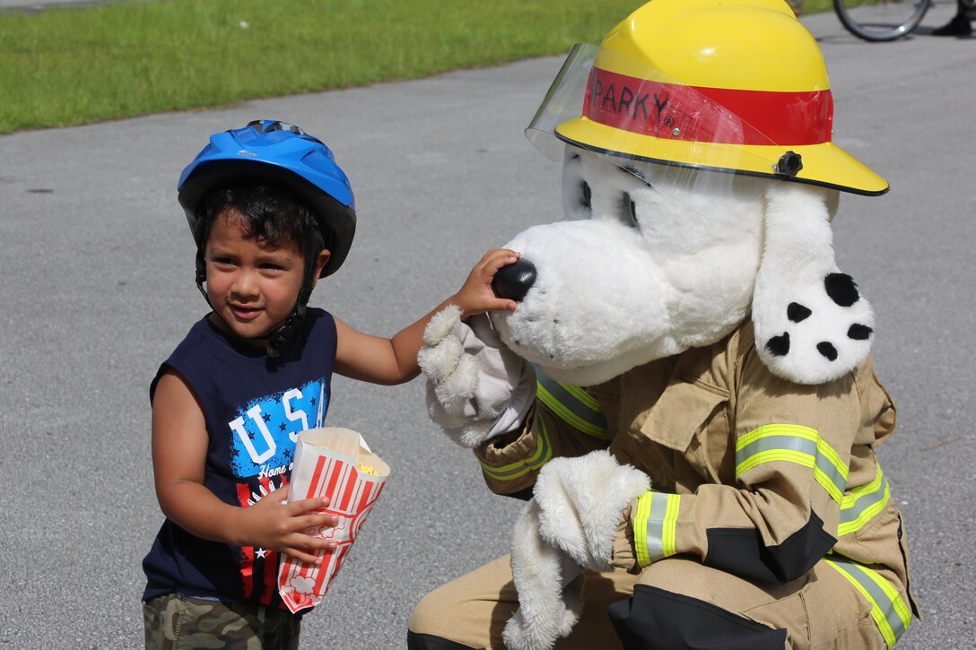 Sparky the Fire Dog meets a young participant during the first Independence Day Youth Parade at Marine Corps Air Station Cherry Point, N.C., July 4, 2017. The bike parade was organized by housing resident Caitlin Chemelewski as a patriotic and fun event for the kids, and to bring the MCAS Cherry Point community together on Independence Day. Nearly 100 members of the Cherry Point community gathered for the festivities. (U.S. Marine Corps photo by Cpl. Jason Jimenez/ Released)