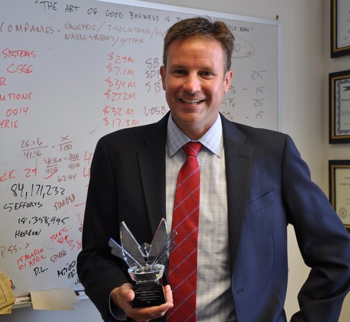 DAHLGREN, Va. (July 7, 2017) – Kris Parker, Naval Surface Warfare Center Dahlgren Division (NSWCDD) deputy for small business, is inspired by a quote – written on his whiteboard in the background – spoken by Sir Michael Gambon in Matthew Vaughn's Layer Cake: "The art of good business is being a good middleman". Parker is holding the Department of the Navy Office of Small Business Program Award for NSWCDD’s first-time achievement of a statutory small business goal – three percent of total contracted dollars to service disabled veteran owned small businesses.  

DON Office of Small Business Programs, small business, Naval Surface Warfare Center Dahlgren Division, NSWCDD, Service Disabled Veteran Owned Small Business Contracts, Disabled Veterans, Veteran Owned Small Business, Statutory Goal Achievement Award, Statutory Goal 
