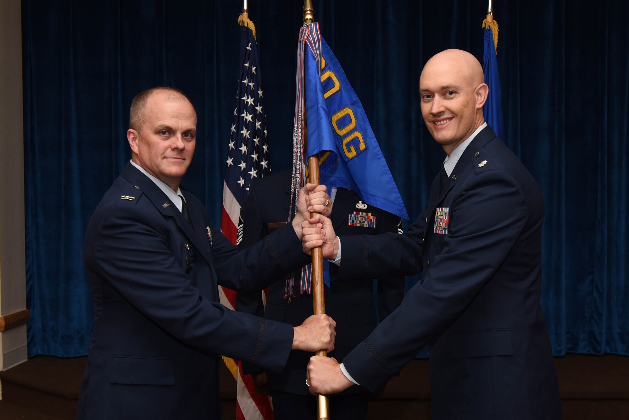 Col. Todd Sauls, 90th Operations Group commander, passes the guidon to Lt. Col. Christopher Maroney, 90th Operations Support Squadron commander, during the 90th OSS change of command ceremony at F.E. Warren Air Force Base, Wyo., July 7, 2017. The ceremony signified the transition of command from Lt. Col. John Hundley. (U.S. Air Force photo by Airman 1st Class Breanna Carter)