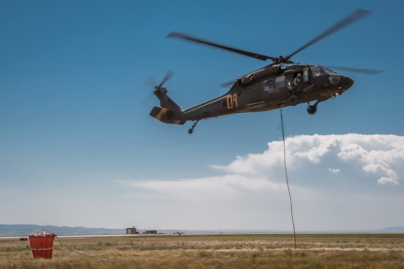 A Wyoming Army National Guard UH-60 Black Hawk helicopter takes off from Laramie Regional Airport July 6, 2017, to assist in fighting the Keystone Fire. Visible at left is the helicopter's water bucket.