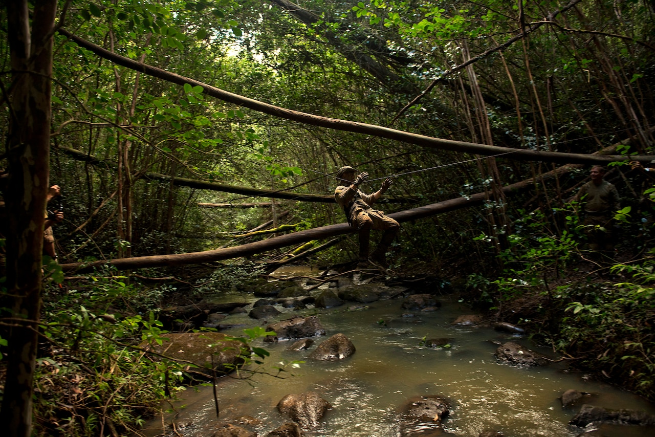 Air Force Senior Airman Andrew Schuler uses a rope bridge to cross a creek during a jungle warfare training exercise on the island of Oahu, Hawaii. Airmen learned how to rig and cross the bridge as part of their training with soldiers. Air Force photo by Master Sgt. Jeffrey Allen