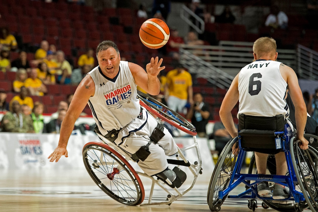 A navy veteran passes a basketball from a teetering wheelchair.