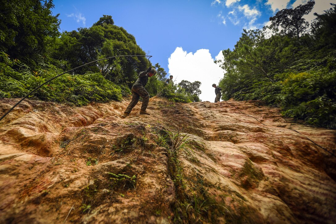 Marines rappel down a mud wall during a jungle warfare course at Camp Gonsalves in Okinawa, Japan, July 5, 2017. The Marines are assigned to Bravo Company, 1st Battalion, 3rd Marine Regiment. Marine Corps photo by Cpl. Aaron S. Patterson